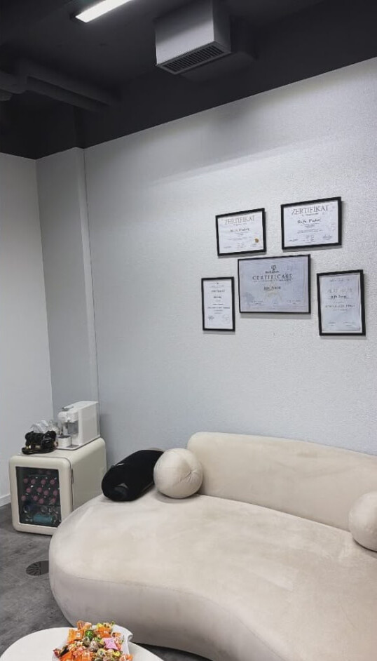 Wartebereich mit Sofa und Zertifikaten an der Wand